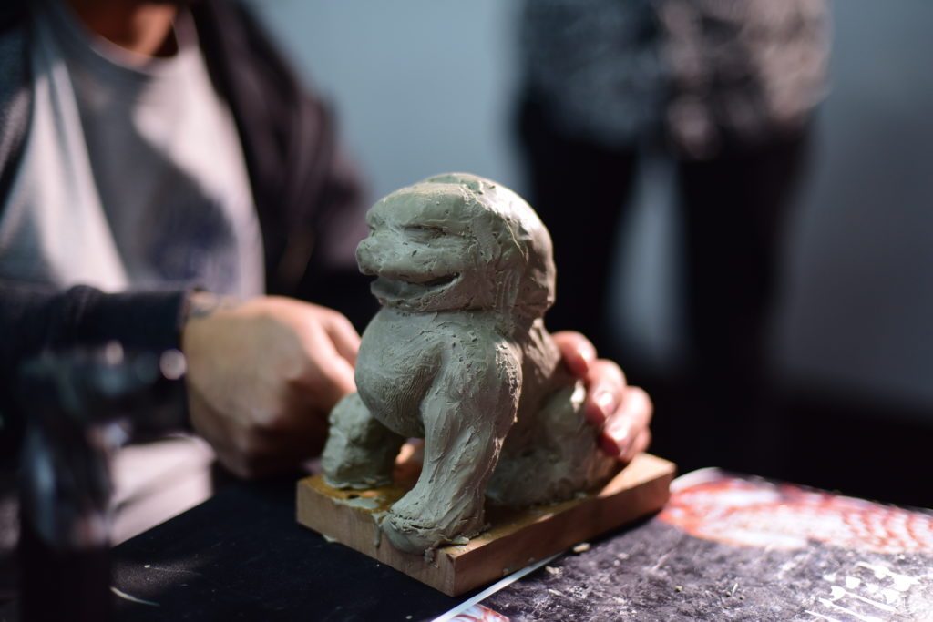 En la imagen se muestran las manos de una persona modelando un dragón.